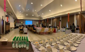 a large banquet hall filled with tables and chairs , where a group of people are gathered for a meeting or event at Poonyamantra Resort