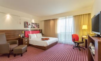 a hotel room with a red and white bed in the center of the room at Hampton by Hilton Exeter Airport