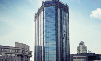 A large building with multiple windows on the side and one at the top in front at Howard Johnson Huaihai Hotel Shanghai