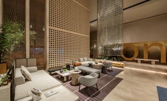 The hotel lobby features an open concept design with couches and tables along the wall at ICON LAB Hotel Shenzhen Futian