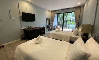 a hotel room with two beds , a television , and a balcony overlooking a pool area at Maikaew Damnoen Resort