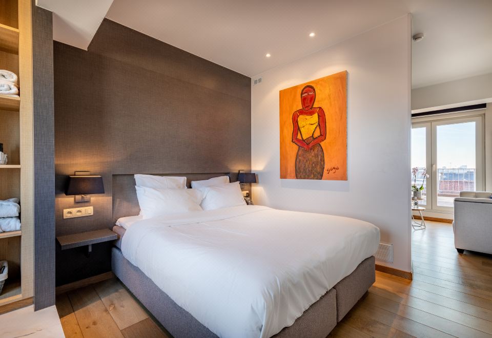 a large bed with white linens is in a room with wooden floors and a painting on the wall at Hotel Carlton