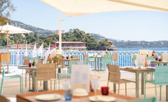 an outdoor dining area with tables and chairs set up for a meal , surrounded by a beautiful view of the ocean at Monte-Carlo Bay Hotel & Resort
