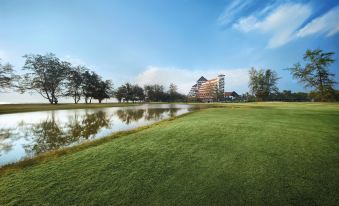 a golf course with a lake in the background and a building on the right side at Resorts World Kijal