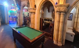 a pool table is in the center of a room with stone arches and other tables at Empire Hotel