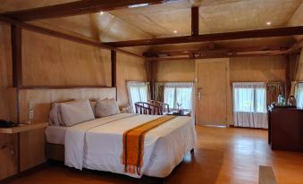 a large bed with white sheets and a wooden headboard is in a room with wooden floors and walls at Khas Parapat