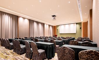 A spacious event room is arranged with tables and chairs positioned in front of the stage at Vienna International Hotel (Baoting Center)