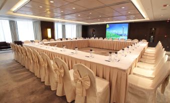 A spacious room is arranged with long tables and chairs for hosting events or functions at Prudential Hotel
