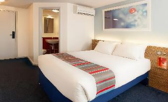 a large bed with a blue base and white pillows is in a hotel room at Travelodge Porthmadog