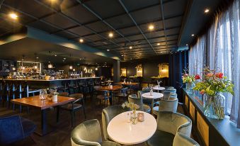 a modern restaurant with tables and chairs , a bar area , and a large window at Van der Valk Hotel Volendam