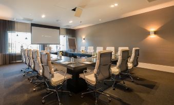 a conference room with a large table , chairs , and a projector screen , ready for meetings or presentations at Van der Valk Hotel Volendam