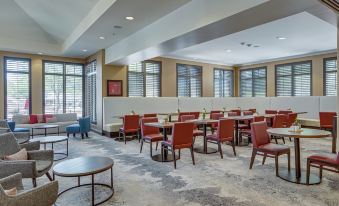 a large , well - lit dining room with multiple tables and chairs arranged for a group of people at Hilton Garden Inn Phoenix Airport North