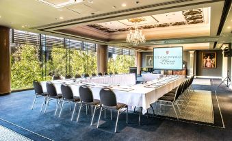 "a large conference room with multiple tables and chairs , a screen displaying "" stamford plaza ,"" and a chandelier hanging from the ceiling" at Stamford Plaza Adelaide