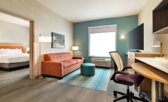 a modern living room with a couch , a chair , a tv , and a desk in the corner at Home2 Suites by Hilton Ogden