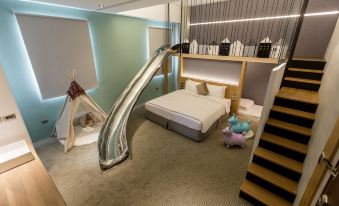 a modern bedroom with a bed , slide , and play area for children , complete with a wooden floor and a canopy at Green Hotel