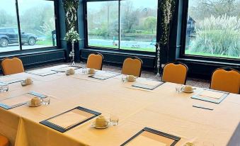 a long dining table set up for a meeting , with chairs arranged around it and a window in the background at Shillingford Bridge Hotel