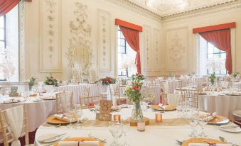 a beautifully decorated banquet hall with multiple dining tables set for a wedding reception , featuring white tablecloths and gold napkins at Lumley Castle Hotel