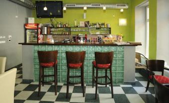 a modern bar with green walls , wooden bar stools , and a checkered floor , along with various beverages and food items on display at Hotel City