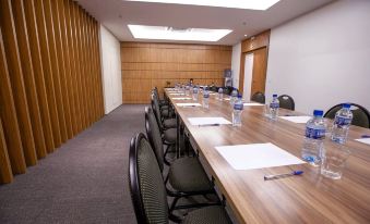 a large conference room with wooden walls , a long table set for a meeting , and several chairs arranged around it at Hplus Vision Executive