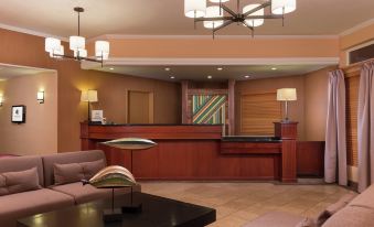 a hotel lobby with a large wooden reception desk , multiple chairs , and a television mounted on the wall at DoubleTree by Hilton Portland - Tigard