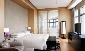 The modern bedroom features large windows, a white bed in the middle, and an elegant ensuite bathroom with a spacious shower and sleek fixtures at Bangkok Marriott Hotel Sukhumvit