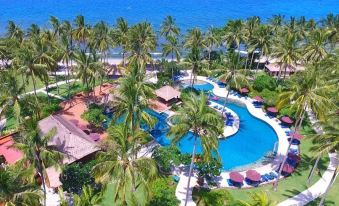 aerial view of a resort with a large pool surrounded by palm trees and a beach at Holiday Resort Lombok