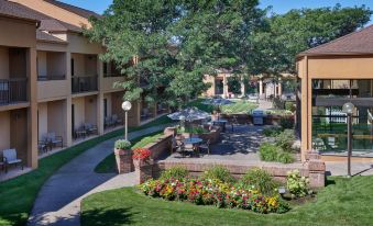 an apartment complex with multiple buildings , a patio area , and a flower garden , under a clear blue sky at Courtyard Detroit Dearborn