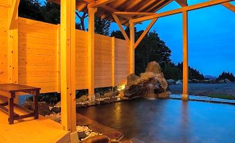 a wooden structure with a pool of water in front of it , surrounded by rocks at Ryokan Warabino