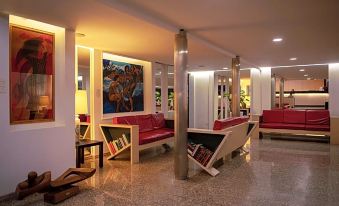a modern hotel lobby with red couches , a painting on the wall , and various seating arrangements at Hotel Califfo