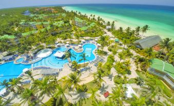 aerial view of a resort with a large pool surrounded by palm trees and a beach in the background at Tryp Cayo Coco