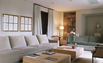 a modern living room with a white couch , a wooden coffee table , and a bookshelf at Parador de La Granja