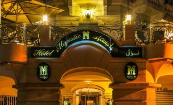 a grand entrance to a hotel , with its name displayed in green and blue neon lights at Majestic Hotel