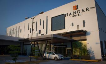 "a modern hotel building with the name "" hanger hotel "" on it , and a car parked in front" at Hangar Inn Guadalajara Aeropuerto