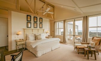 a large , well - made bed with white linens and a headboard is in a bedroom with large windows at Rosewood Cape Kidnappers