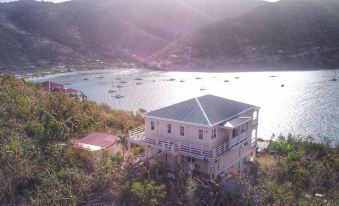 an aerial view of a house surrounded by mountains , overlooking a body of water and boats in the distance at Ocean View Villas