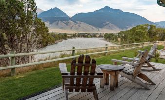a wooden deck overlooking a river , with several chairs placed on the deck for relaxation at Yellowstone Valley Lodge, Ascend Hotel Collection