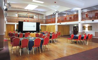 a large conference room with multiple tables and chairs , a stage , and a balcony , set up for an event at Royal Maritime Hotel