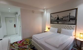 a hotel room with a white bed , a colorful carpet , and a framed picture on the wall at A Hotels Glostrup