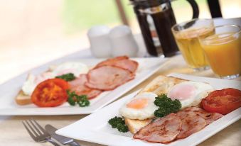 two plates of breakfast food , including ham , eggs , and toast , are placed on a dining table at Murray Downs Resort