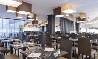 a large , modern restaurant with multiple dining tables and chairs arranged in an open dining area at Hotel Bristol 4 Sup