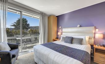 a modern hotel room with a large bed , white headboard , and purple walls , along with a balcony view at Tides Hotel