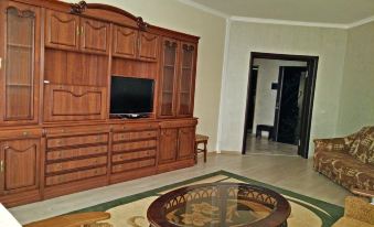 a living room with a large wooden entertainment center , a flat - screen tv mounted on the wall , and a dining table in the background at Luxury Apartment