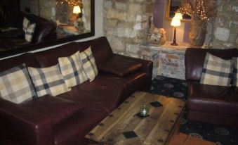 a cozy living room with two brown leather couches , one on the left and the other on the right at George Inn