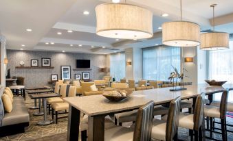 a dining area with a long wooden table and several chairs , creating a comfortable atmosphere for guests at Hampton Inn Hallandale Beach-Aventura