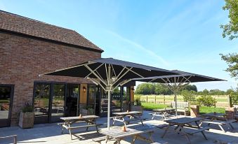 an outdoor dining area with multiple picnic tables and umbrellas , providing shade and seating for guests at The Bowl Inn