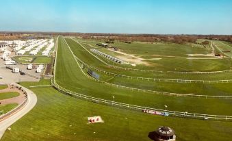 an aerial view of a large green field with a few small houses and trees in the distance at Hilton Garden Inn Doncaster Racecourse