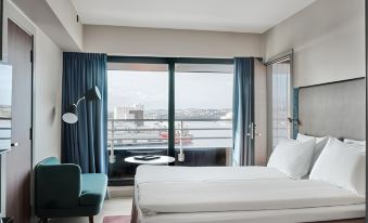 a hotel room with a large bed , blue curtains , and a window offering a view of the city at Radisson Blu Caledonien Hotel, Kristiansand