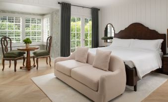 a cozy bedroom with a large bed , a couch , and a chair , all situated near a window at The Inn at Rancho Santa Fe
