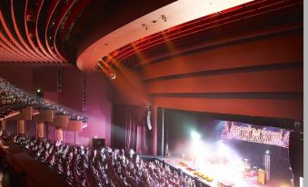 a large , red - lit auditorium with an open stage and people watching an event taking place at Crown Metropol Perth