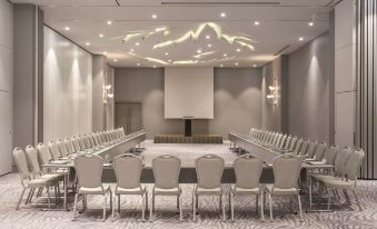 a conference room with white chairs arranged in a semicircle around a table , and a projector screen mounted on the wall at Wyndham Grand Istanbul Kalamış Marina Hotel